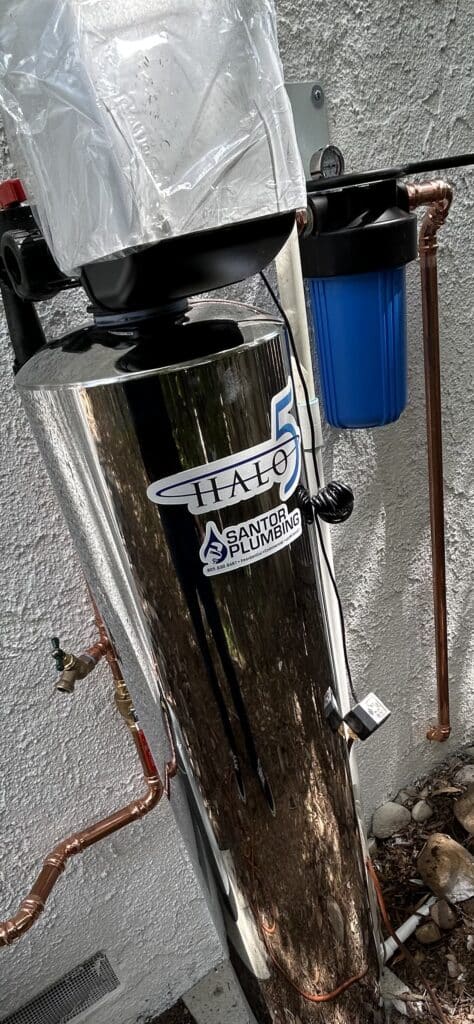 Santor Plumbing water filtration system with copper pipes and blue filter cartridge.