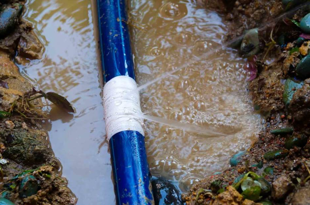 Damaged blue water line with leak and repair tape, illustrating main water line repair cost factors.
