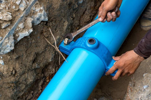 Plumber tightening wrench on blue water line pipe repair.