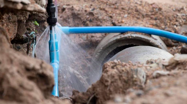 Damaged main water line with leak and repair pipe in Ventura County soil.